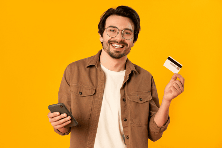 Homem sorrindo segurando um cartão de benefícios flexíveis e um celular