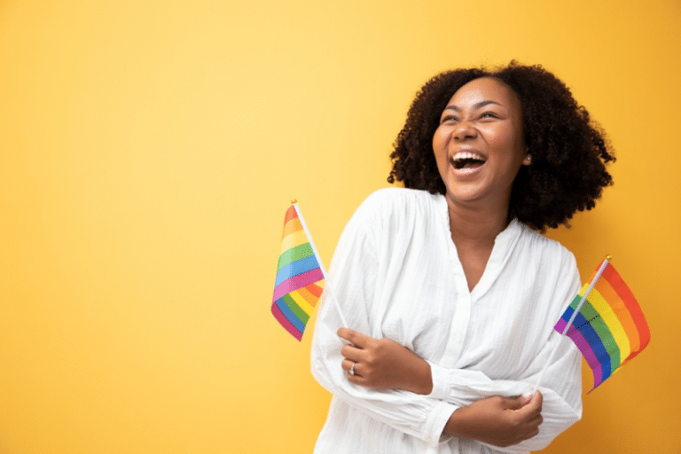 Mulher feliz com duas bandeiras representando o Dia Internacional do Orgulho LGBTQIAP+