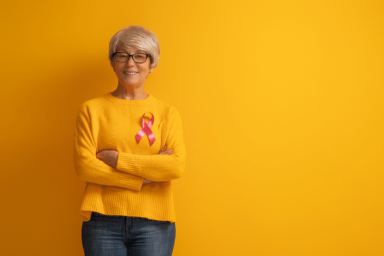 Mulher vestindo uma blusa amarela com um laço rosa representando a campanha Outubro Rosa